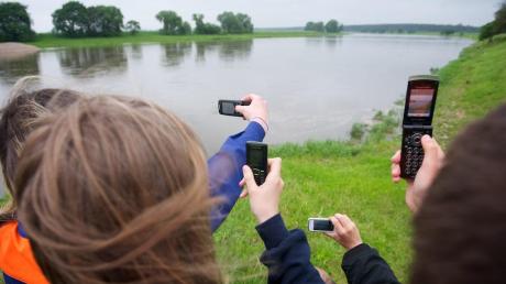 Jugendliche erfassen mit ihren Handys eine Flusslandschaft