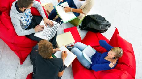 Jugendlich sitzen auf Sitzsäcken und  lernen zusammen